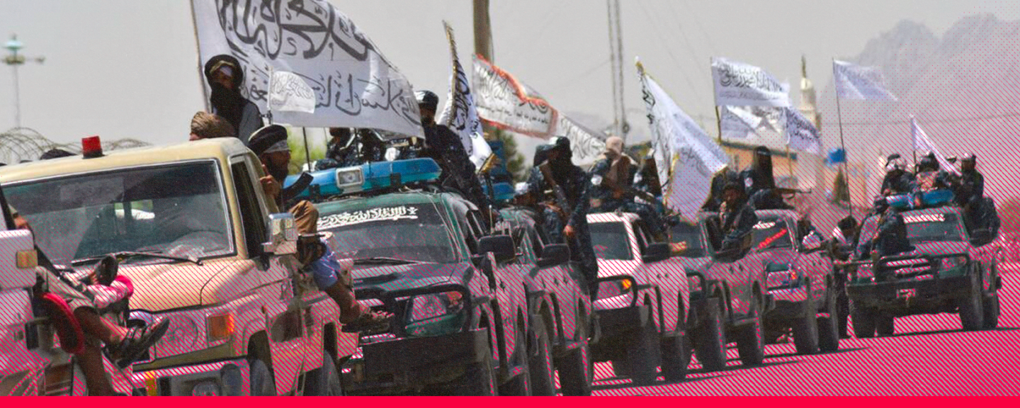 En konvoj med talibanfordon kör längs en väg i Afghanistan. Beväpnade män står på och omkring fordonen och håller upp talibanernas vita flaggor.